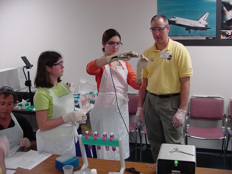 John Perkey helps student with heat sealing a flight sample tube