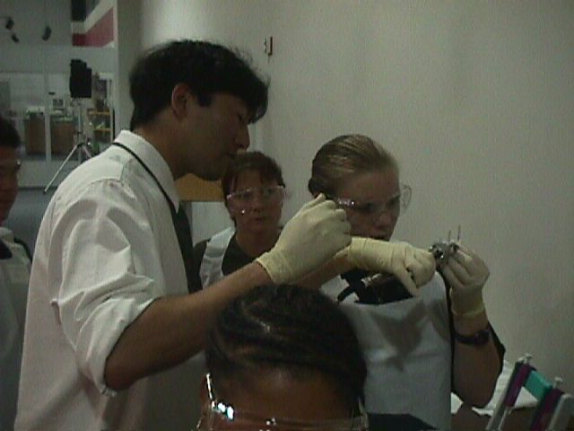 Joe Ng is assisting Katie Cauthen while she is sealing one end of the flight sample.